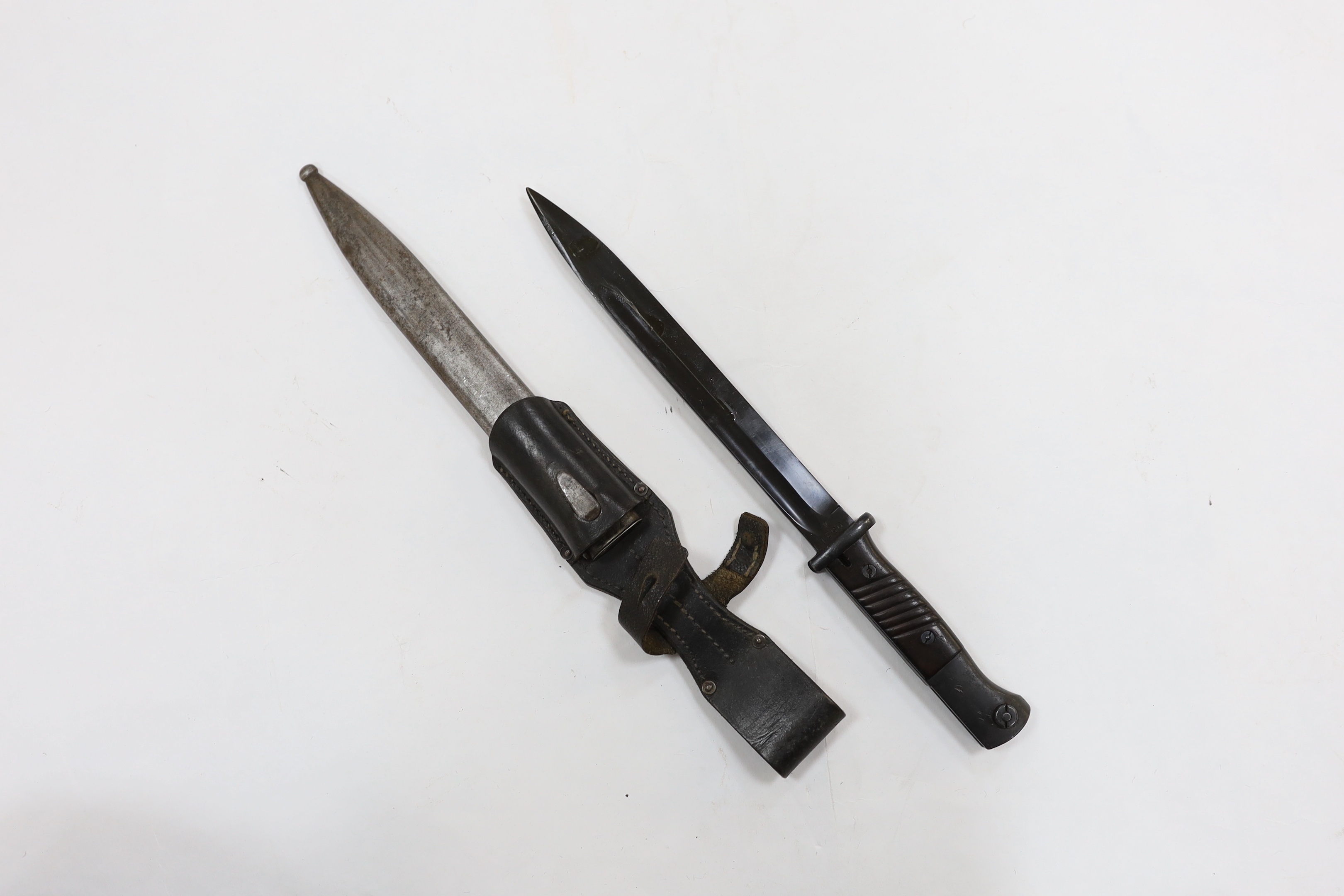 Four bayonets; two Mauser bayonets in scabbards, an American M8A1 carbine bayonet in a scabbard, and another
